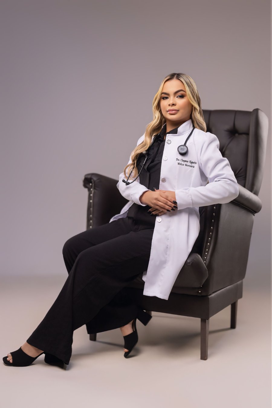 Dra. Chayanne Nogueira em uniforme veterinário (scrubs azul-marinho) com estetoscópio.